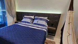 Une chambre à coucher avec un lit, une table de chevet et une fenêtre avec des rideaux.