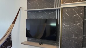 Un salon moderne avec un téléviseur à écran plat fixé au mur, lequel est orné de panneaux imitant le marbre.