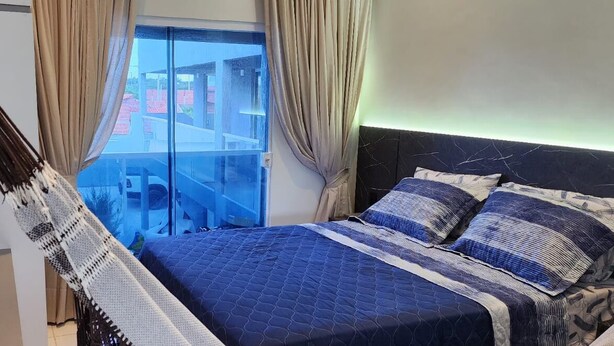 Une chambre à coucher avec un lit, des rideaux et une vue sur les bâtiments environnants.