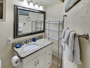 A bathroom with a sink, mirror, towel rack, and a painting on the wall. - Something's Fishsea by Miss Kitty’s (Rockport)