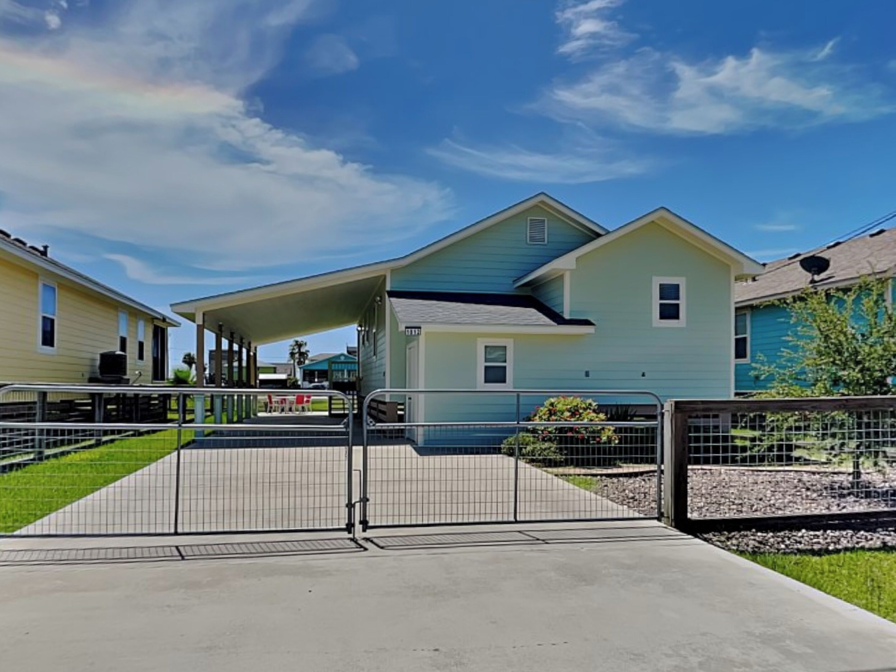 A residential area with houses, a gated entrance, and a clear sky.