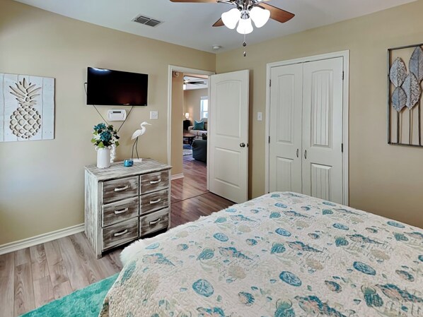 A bedroom with a bed, dresser, TV, and a ceiling fan. - Gulf Coast Getaway by Miss Kitty’s (Rockport)