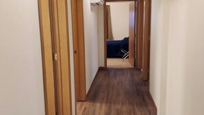 Un couloir étroit avec des portes en bois et un plancher en bois foncé.