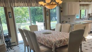 A dining area with a hexagonal tiled floor, a table with floral tablecloth, and chairs. - Spacious Vacation 4BR Home Near Southold Beach, Greenport, and Top Wineries (Southold)