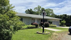 A residential house with a well-maintained lawn, a street lamp, and a driveway. - Spacious Vacation 4BR Home Near Southold Beach, Greenport, and Top Wineries (Southold)