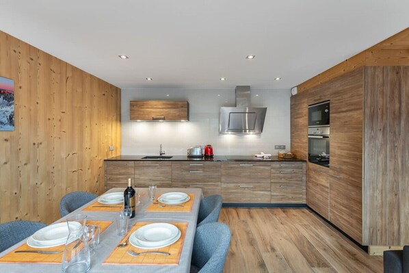 A modern kitchen with wooden cabinetry, a built-in microwave, and a stainless steel range hood.