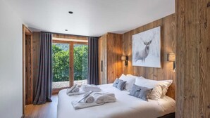 Un dormitorio con una cama grande, paneles de madera, vistas a la vegetación y un cuadro de un ciervo en la pared.