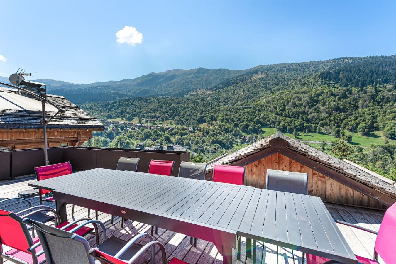 A wooden deck with a table and chairs, overlooking a mountainous landscape.