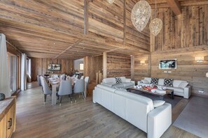 Un vaste espace de vie doté d’un plafond en bois, d’un coin repas et d’un ensemble de canapés.