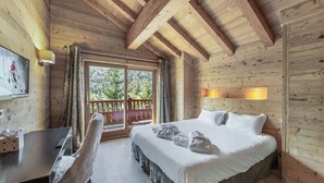 Una habitación de cabaña de madera con cama, escritorio y ventana con cortinas.