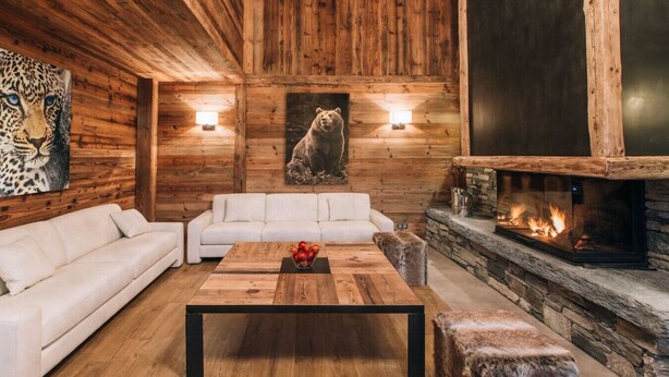 Una sala de estar acogedora con chimenea, sofás blancos y una mesa de centro de madera.