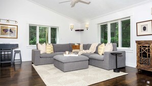 Ein Wohnzimmer mit Ecksofa, Couchtisch, Kamin und großen Fenstern.