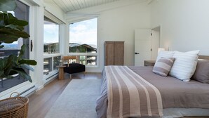 A bedroom with a large bed, a view of the city, and a balcony with a chair and table. - Luxury 4BR Condo | Pool, Hot Tub & Mtn Views! (Snowmass Village)