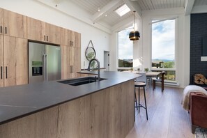 A modern kitchen with wooden cabinets, a stainless steel refrigerator, and a large island with a sink.
