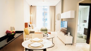 Ein modernes Hotelzimmer mit Essbereich, Wohnbereich und Badezimmer.