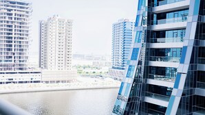 Ein modernes Hochhaus mit Glasfassade, ein Fluss im Vordergrund und weitere Gebäude im Hintergrund.