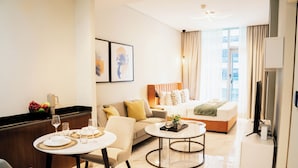 Ein modernes Hotelzimmer mit Sofa, Esstisch, Couchtisch, Fernseher und Bett.