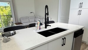 Een moderne keuken met een wit aanrecht, een zwarte kraan en grijze kastjes.