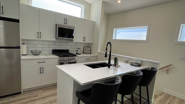 Een moderne keuken met een centraal eiland, barkrukken en een roestvrijstalen koelkast.
