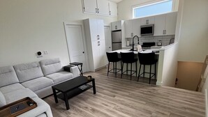Een moderne woonkamer met een bank, een salontafel en een keukenhoek met een eethoek.