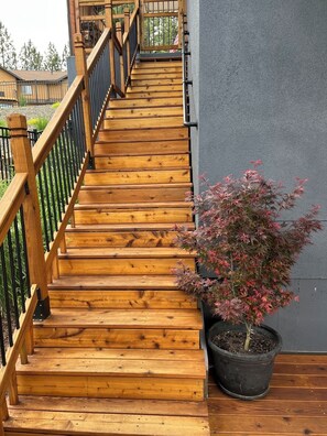 A wooden staircase with a railing, leading to a balcony with a potted plant. - B&B with fireplace, 4 TV's, deck, billiards, firepit & great view of Hayden Lake (Coeur d'Alene)