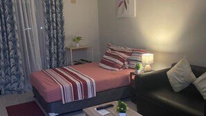 A modern bedroom with a bed, a bedside table, a nightstand, a sofa, and a small table. - Studio with Balcony at Saekyung 956 (Lapu-Lapu City)