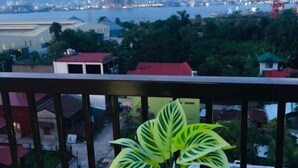 A balcony with a wooden table, a red mug, and a potted plant. - Studio with Balcony at Saekyung 956 (Lapu-Lapu City)