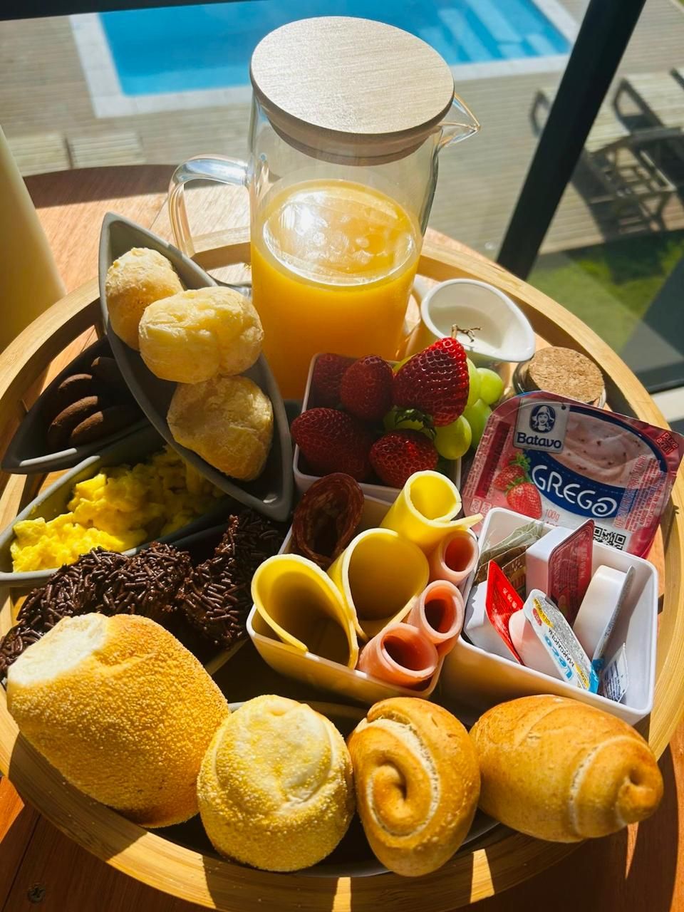 Bandeja de desayuno con diversas opciones como pasteles, frutas y una jarra de jugo de naranja.