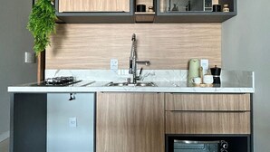 A modern kitchen with a built-in microwave, a sink, and a compact oven. - Pousada Austral Suítes (Imbituba)