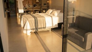 A modern bedroom with two beds, a sofa, and a glass partition. - Pousada Austral Suítes (Imbituba)