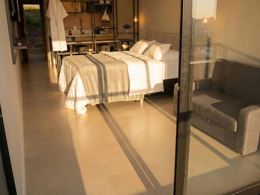 Un dormitorio moderno con dos camas, un sofá y un separador de vidrio.