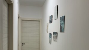 Un couloir avec une porte fermée, un plancher en bois et des œuvres d’art accrochées au mur.