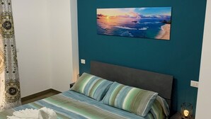 Une chambre à coucher avec un lit, une table de chevet, un tableau accroché au mur et un rideau.