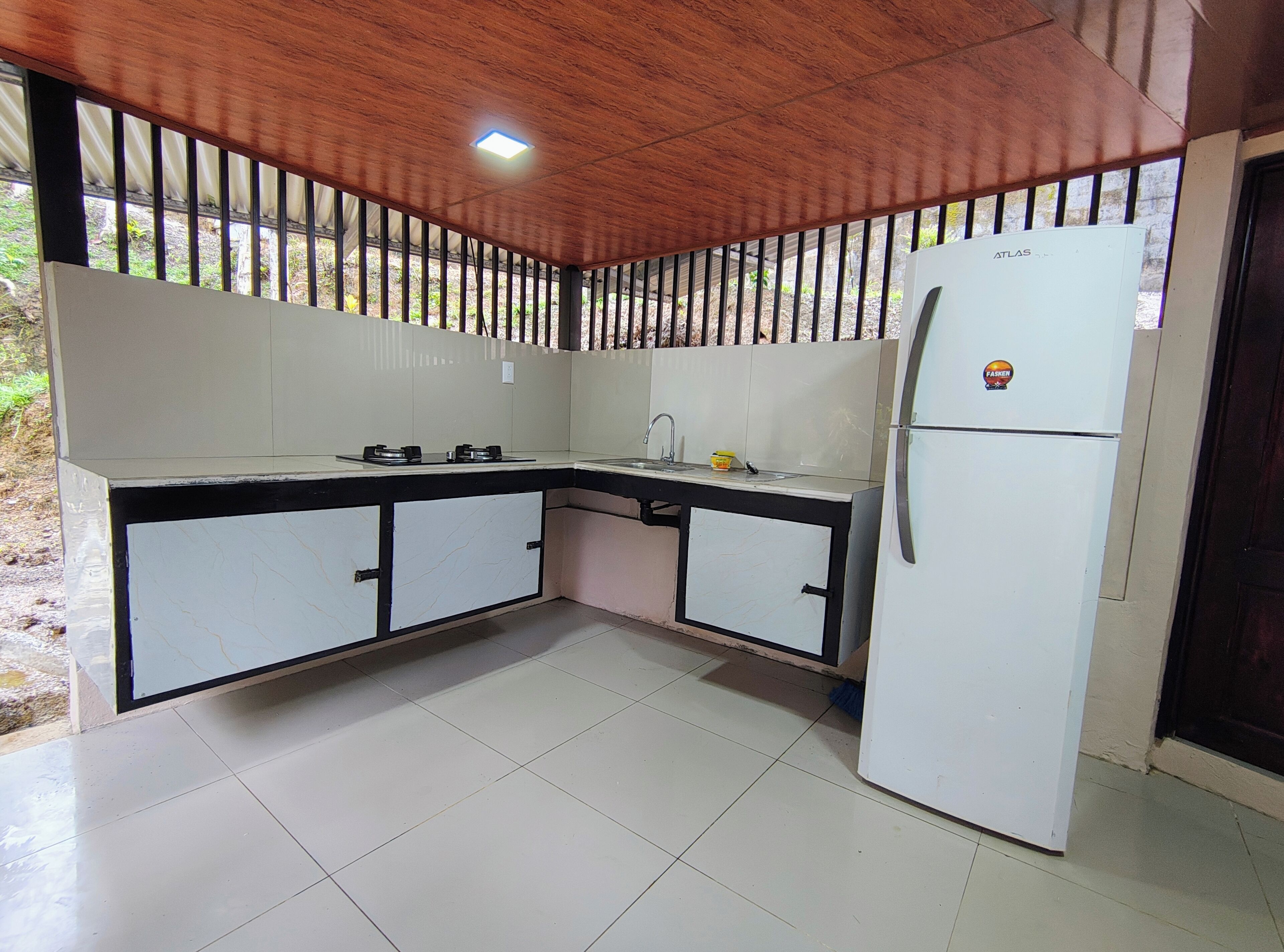 A compact kitchen with a refrigerator, stove, and sink.