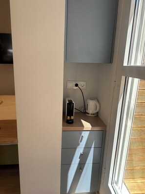 Una kitchenette con cafetera, hervidor eléctrico Krups y toma de corriente.