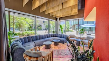 A modern lounge area with a curved sofa, round tables, and a variety of seating options.