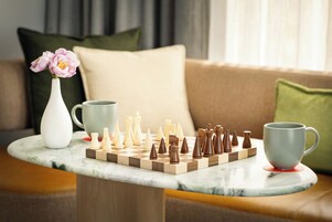 Ein Schachbrett auf einem Marmortisch zusammen mit einer Blumenvase und zwei Tassen.