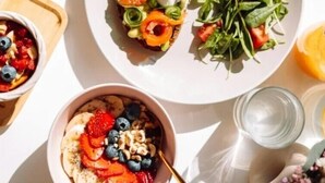 A breakfast setting with a plate of toast topped with salmon, eggs, and greens, a bowl of yogurt with berries, and a glass of water. - The Atlas Hotel Boston Cambridge (Boston)