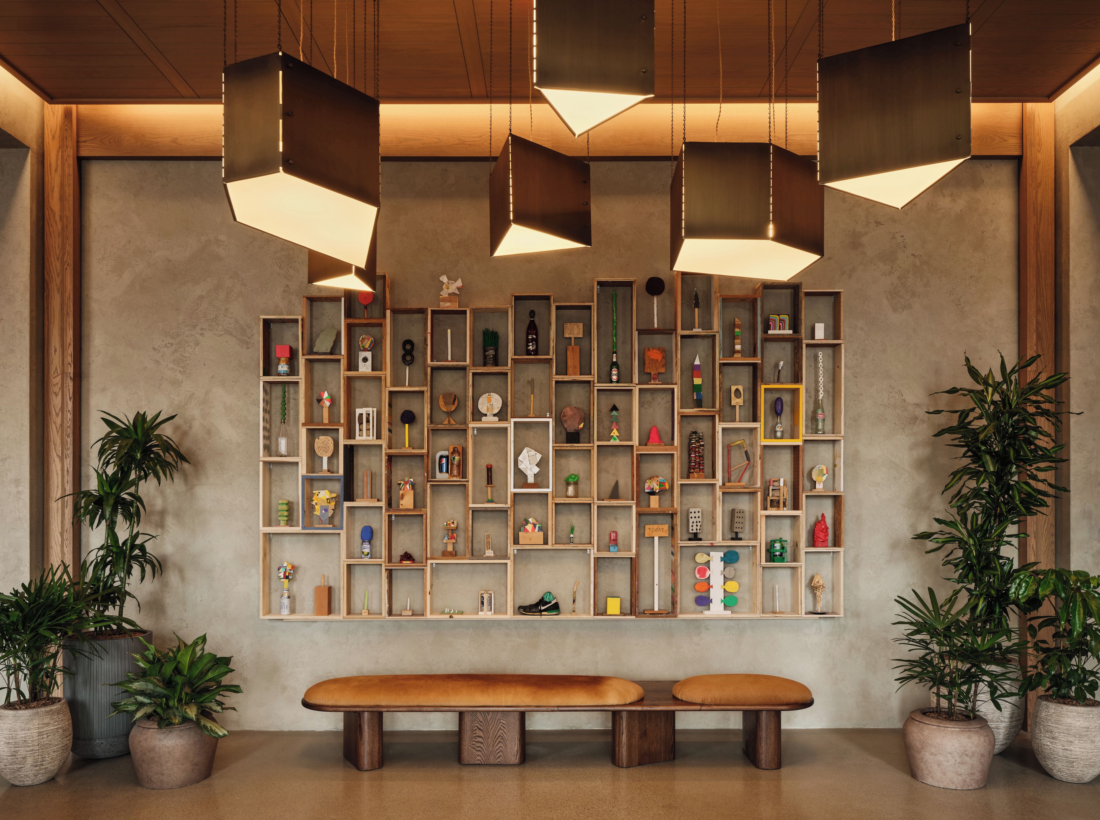 A reception area with a wooden bench, shelves with various items, and hanging pendant lights.