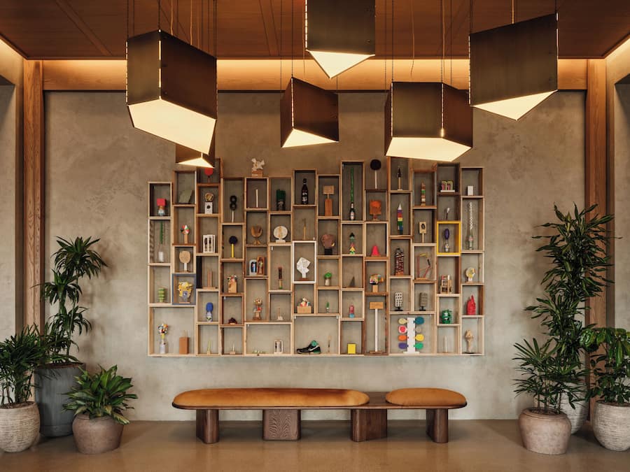 A reception area with a wooden bench, shelves with various items, and hanging pendant lights.