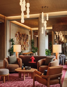 A reception area with a wooden bench, shelves with various items, and hanging pendant lights. at The Atlas Hotel