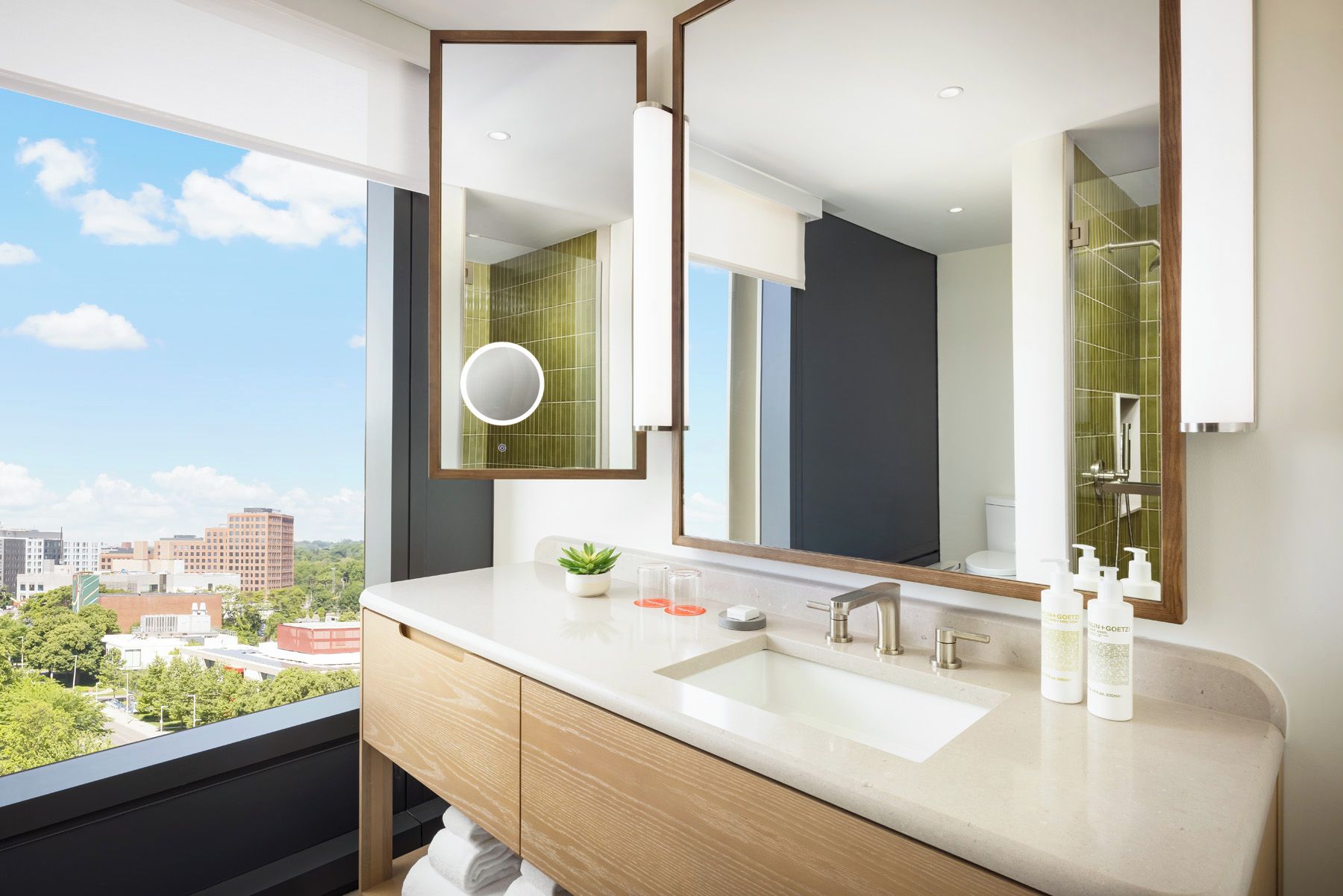 A modern bathroom with a large mirror, a sink, and a toilet.