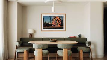 Un comedor moderno con una mesa redonda, seis sillas, un sofá verde y una obra de arte enmarcada en la pared.