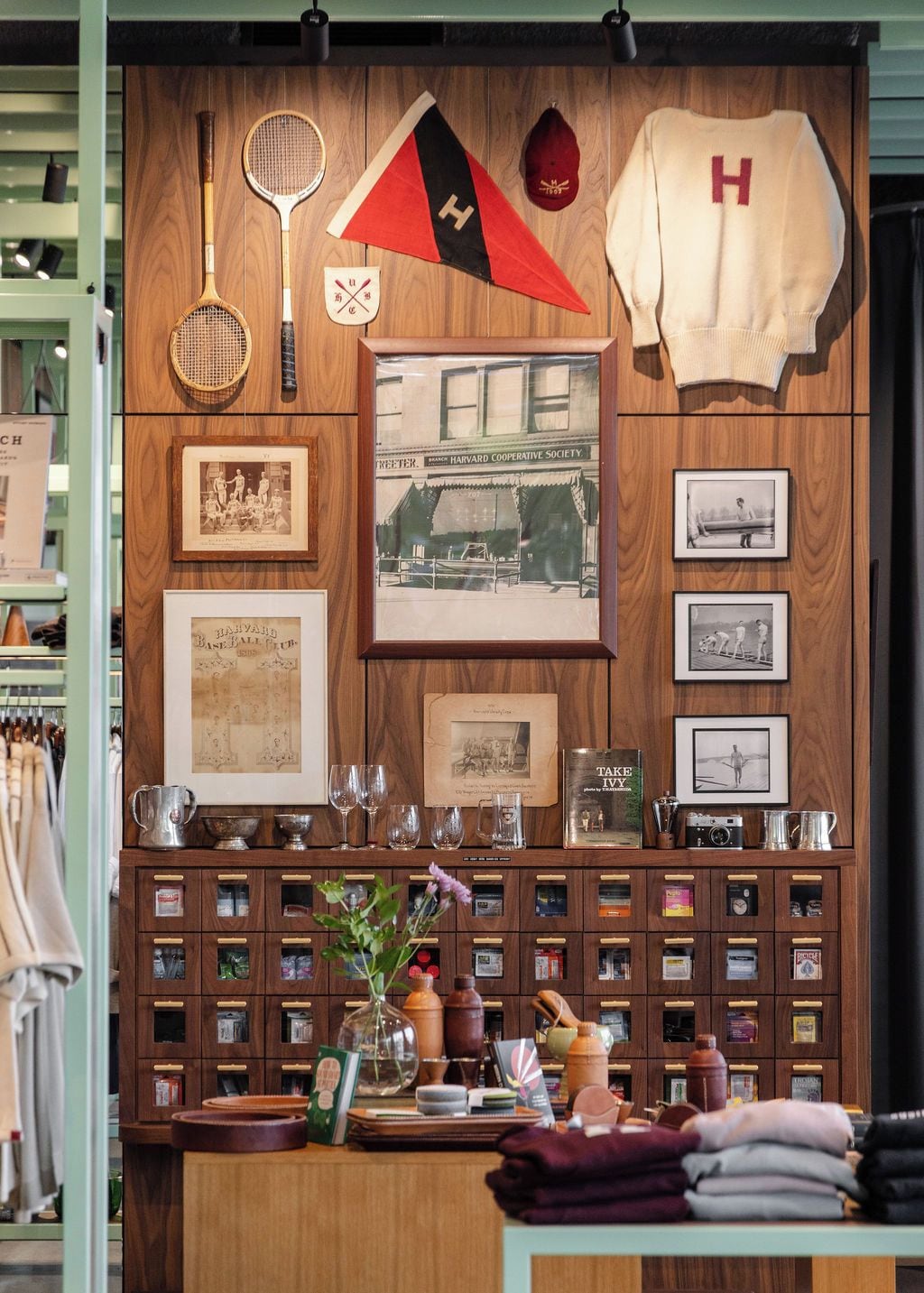 Un mur en bois orné de divers objets, notamment une raquette de tennis, un drapeau, une casquette de baseball ancienne, des photographies encadrées et une collection de bouteilles et de verres anciens.