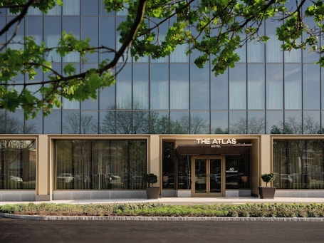 A modern hotel facade with large windows and a sign reading 'The Atlas Hotel.'