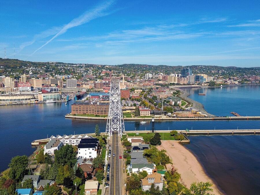 Rannikkokaupunki, jossa näkyy selvästi siluetti, huomiota herättävä silta, merenrantarakennuksia ja kirkas taivas.