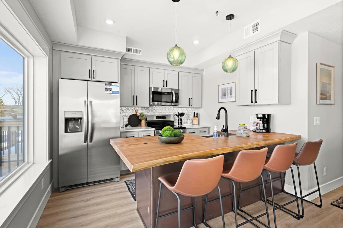 A modern kitchen with a central island, stainless steel appliances, and pendant lighting.