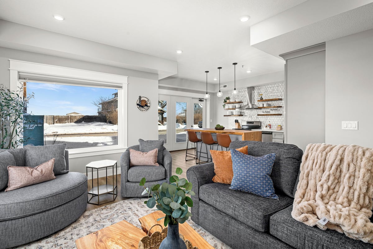 A modern living room with grey sofas, a coffee table, and a large window.