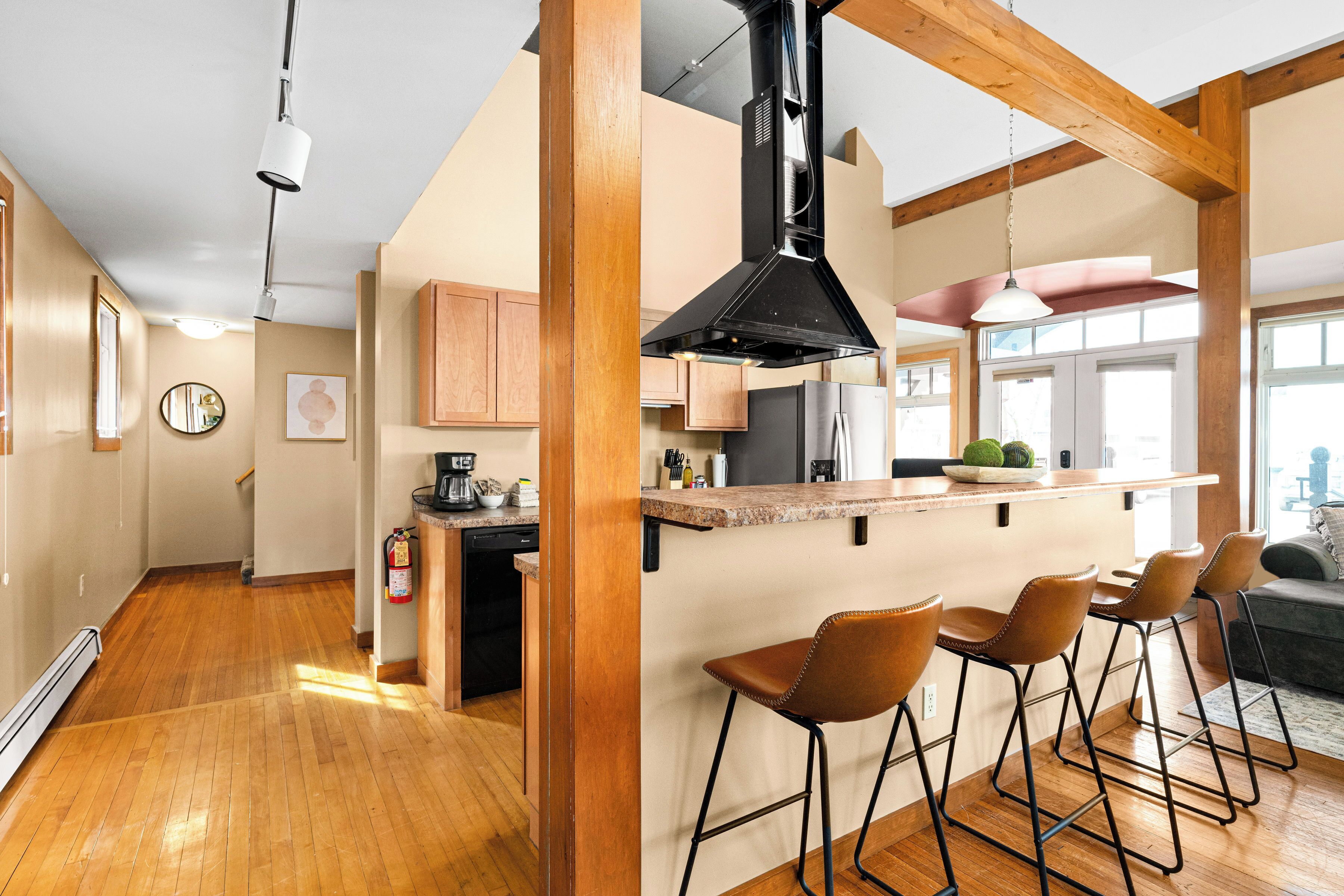 Una cocina moderna con vigas de madera, una isla central con taburetes altos y vistas al área de estar.