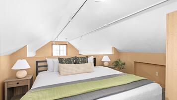 Una camera da letto con un letto, comodini, lampade, una finestra e una pianta.